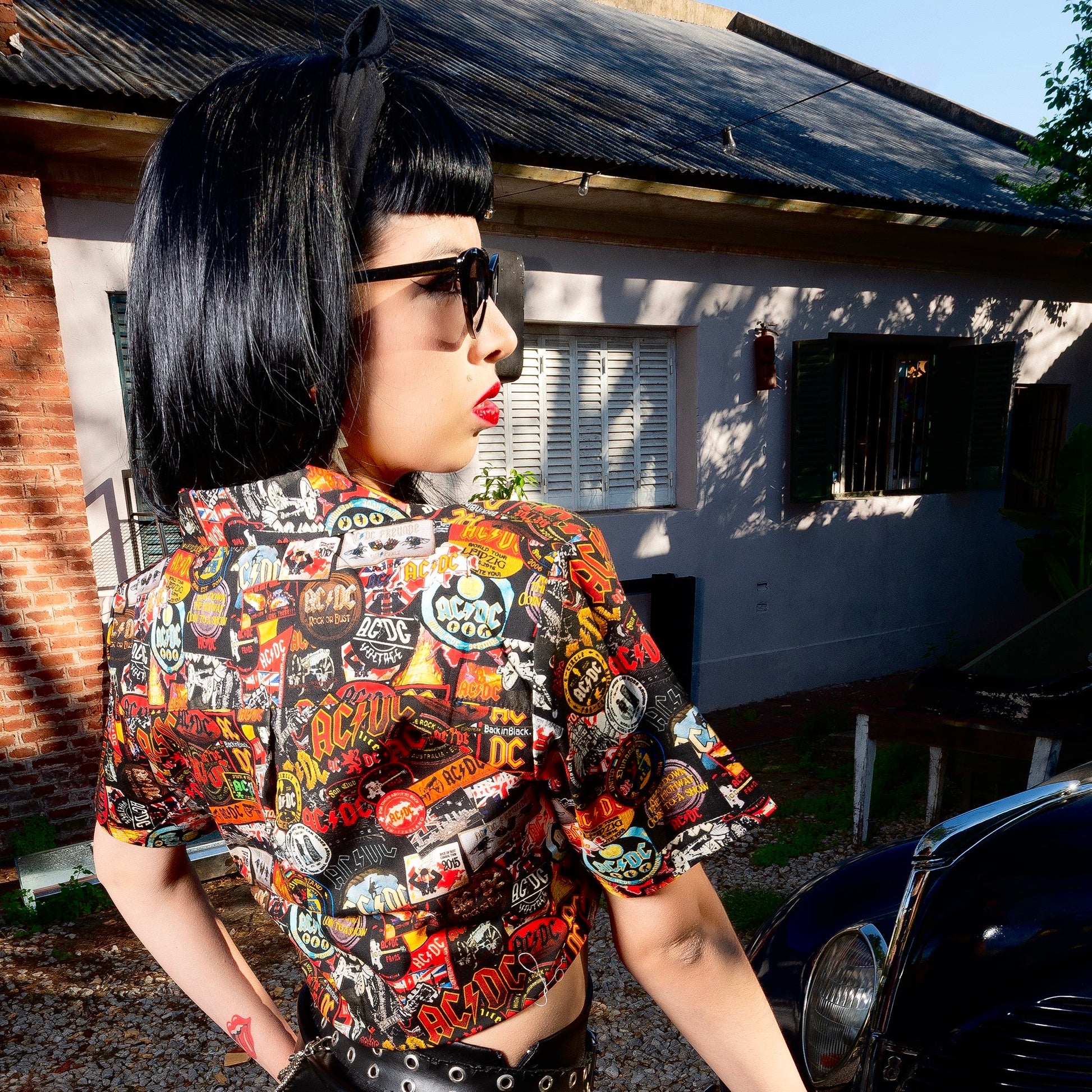 A woman is wearing a high-quality crop top from AC/DC. It is printed with lots of AC/DC patches. Not cheap merchandise, but high quality. 