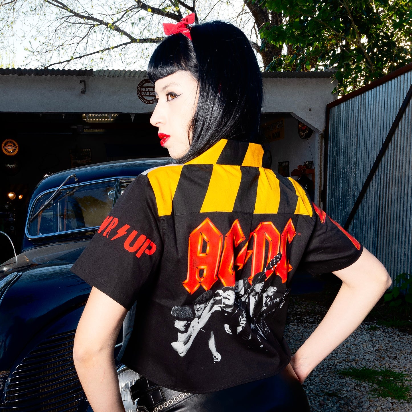 A rock chick wears a high-quality crop top from AC/DC. It features a PWR/UP style print. Not cheap merchandise, but high quality. 